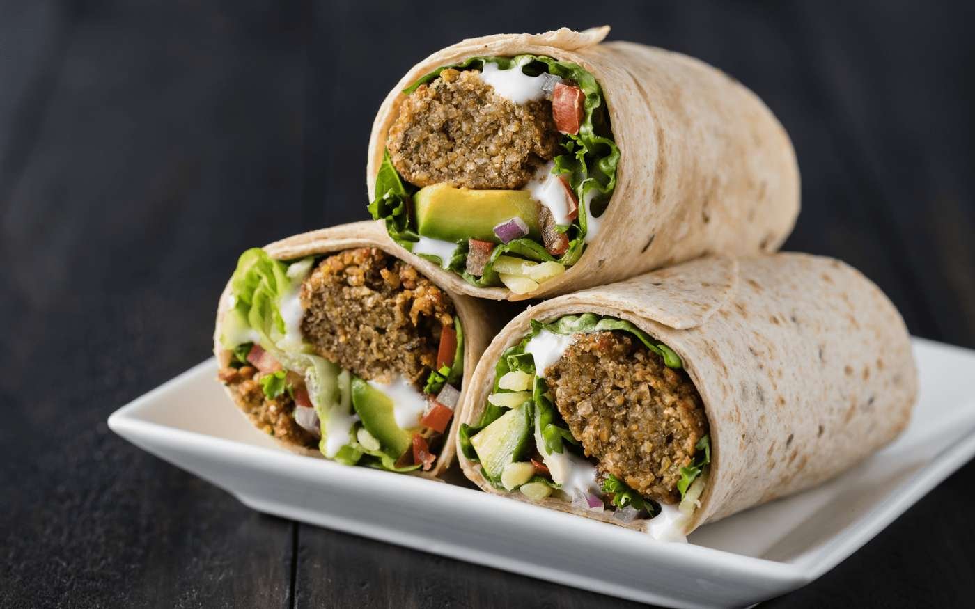 Falafel wraps with lettuce, tomato and avocado on a serving plate